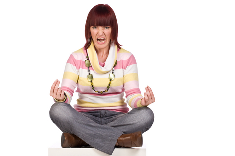 A woman meditating with a horrid angry look on her face.